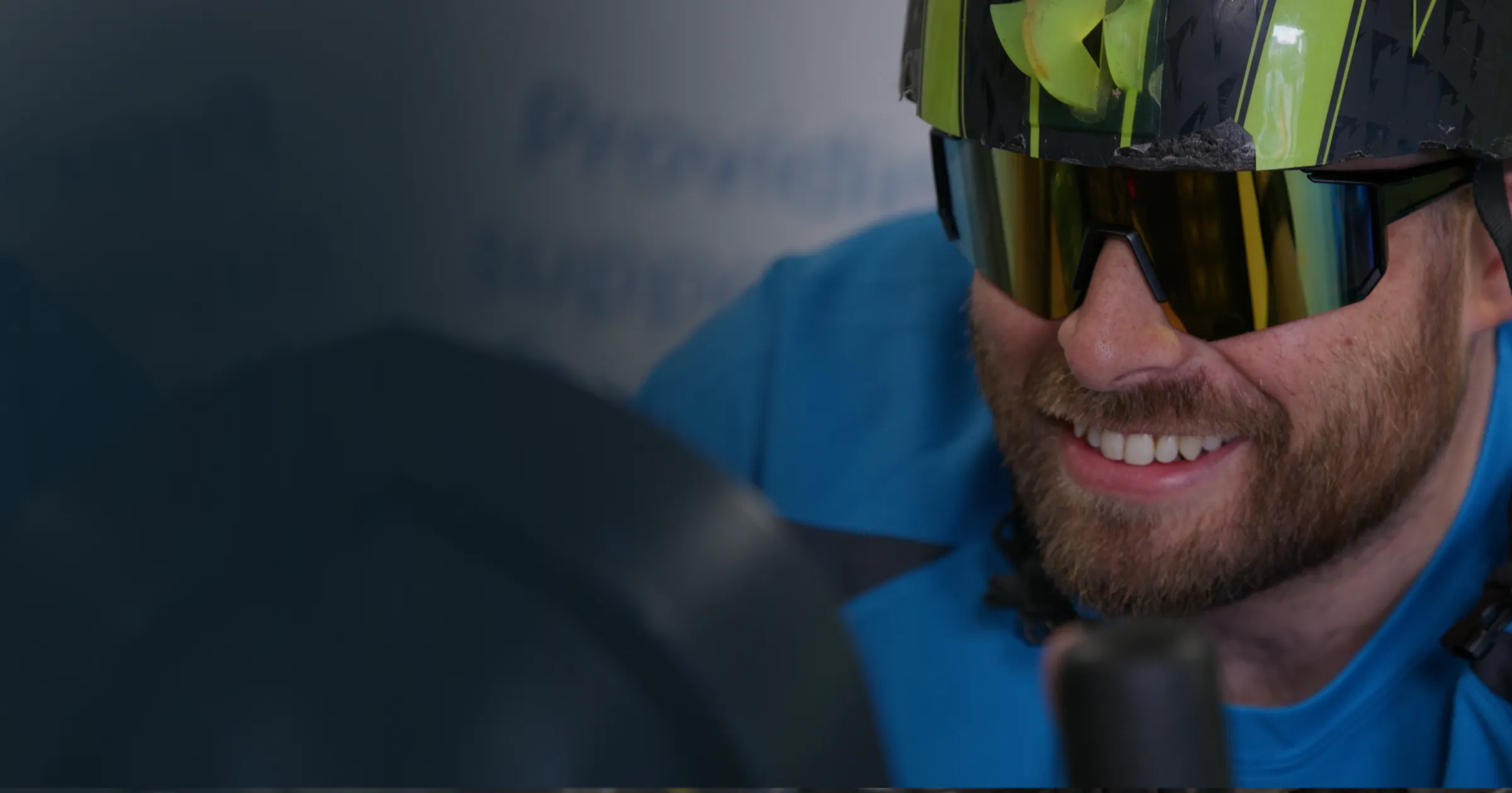 A Boal & Co cycle challenge participant Andrew Cover smiling while riding, wearing a cycling helmet and wraparound sunglasses during the 12-hour charity event filmed by DotPerformance on the Isle of Man